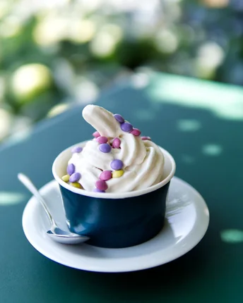 A soft-serve frozen yogurt swirl in a cup, finished with pastel sprinkles.