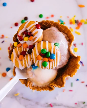 A waffle bowl of frozen yogurt covered in candy pieces and drizzle.